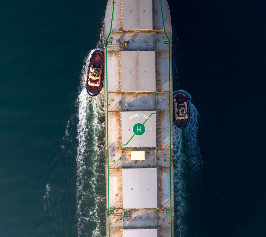 Cargo ship with tugboats, from above