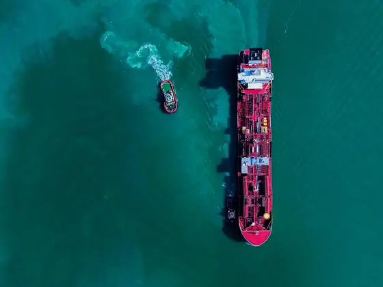 Aerial view of a tanker and tug on green water