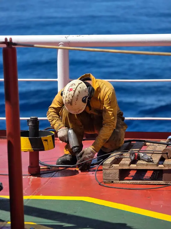 Crew member in a hard hat working on a ship's deck — maritime workforce